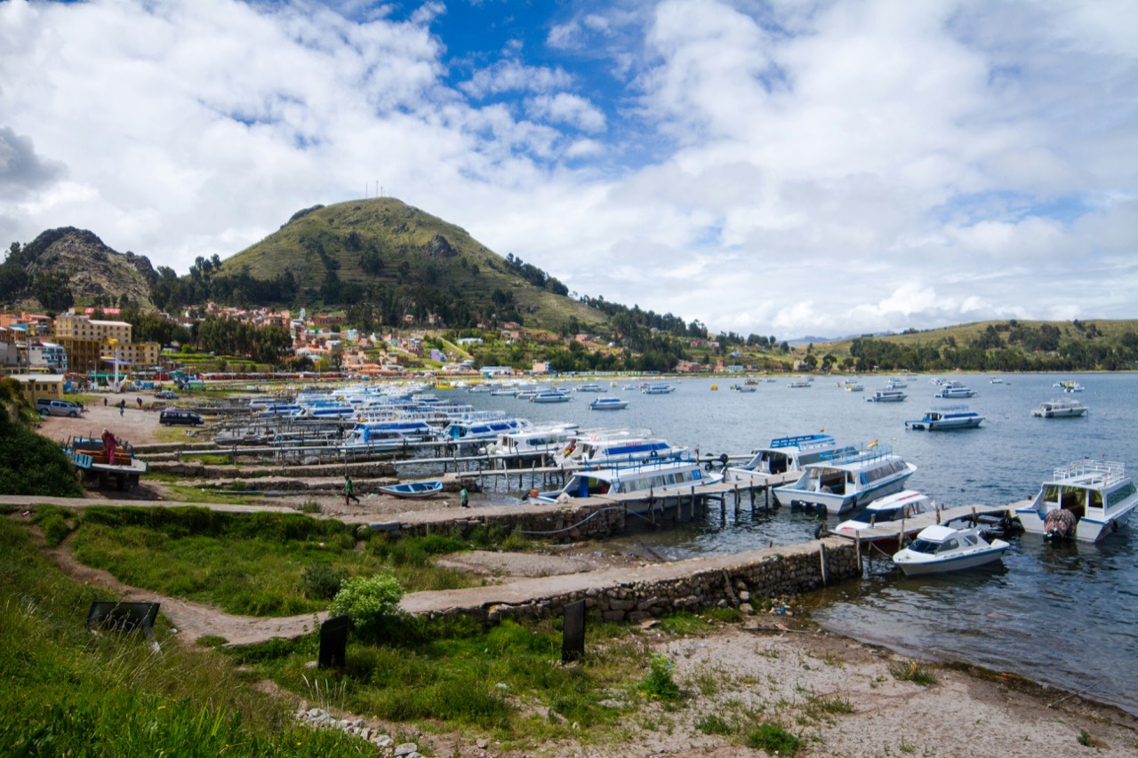 Lode zakotvené pri brehu jazera Titicaca obklopeného kopcami