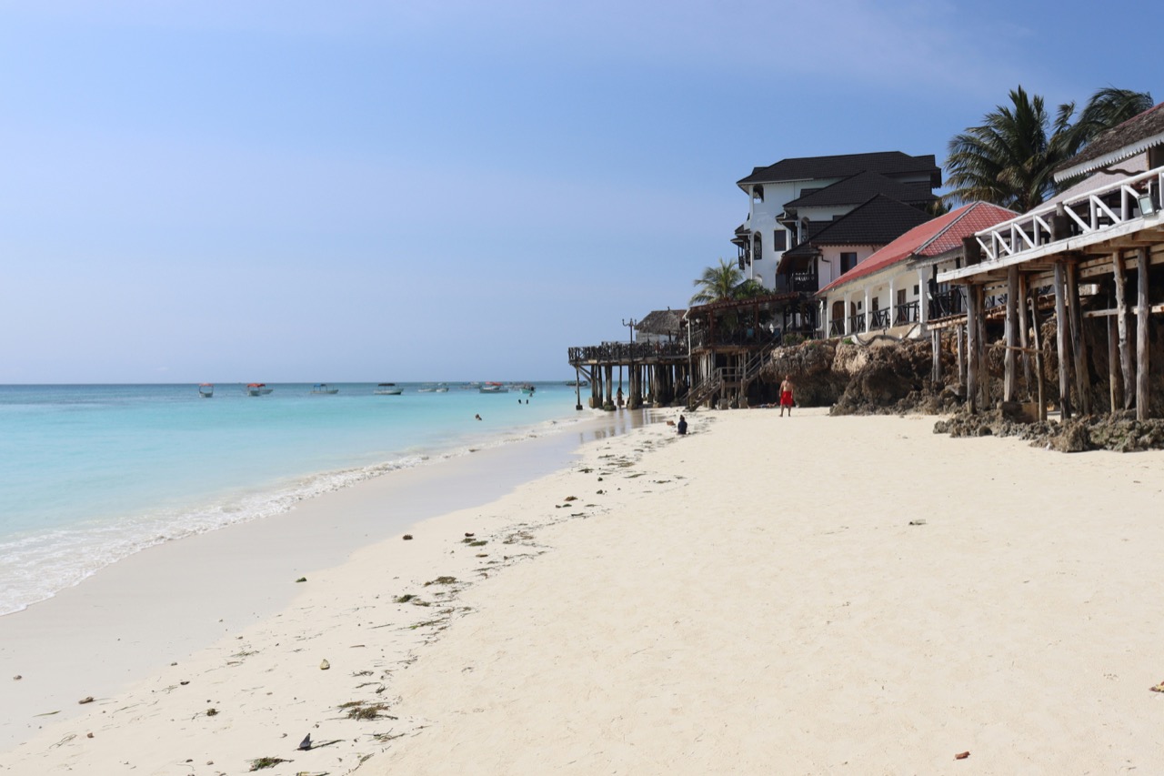 Biela piesočná pláž s rybárskymi domami v dedine Nungwi na severe Zanzibaru
